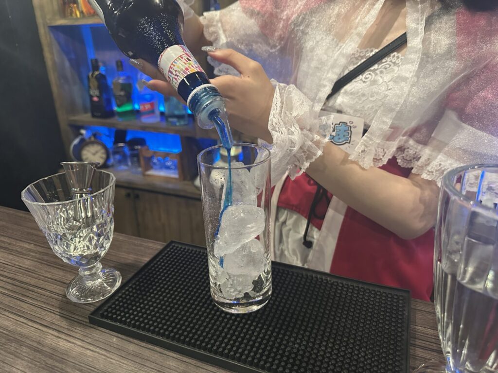 えまさんがグラスにブルーキュラソーを注いでいる