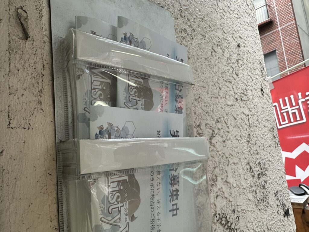 「実験台募集中」と書かれたチラシがチラシ入れに入っている